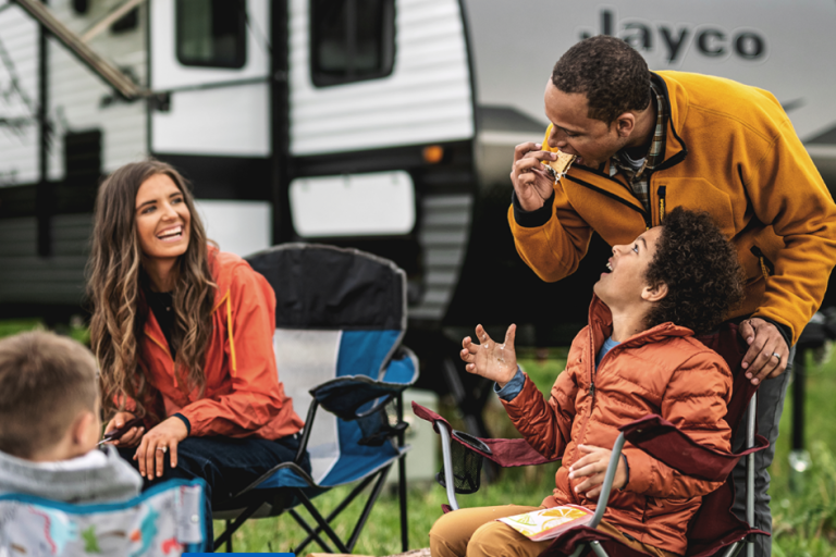 Family enjoying a travel trailer in a picturesque Canadian natural setting
