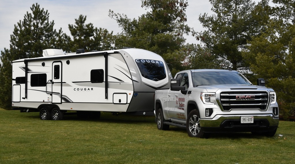 Cougar RV travel trailer hooked up to a truck.

On Grass with trees in background