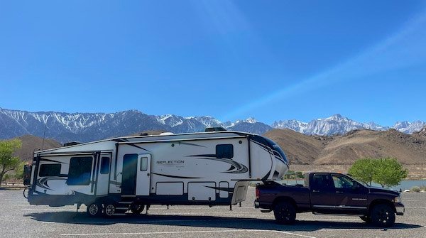 Grand Design Reflection hooked up to a truck with snow covered mountains in background