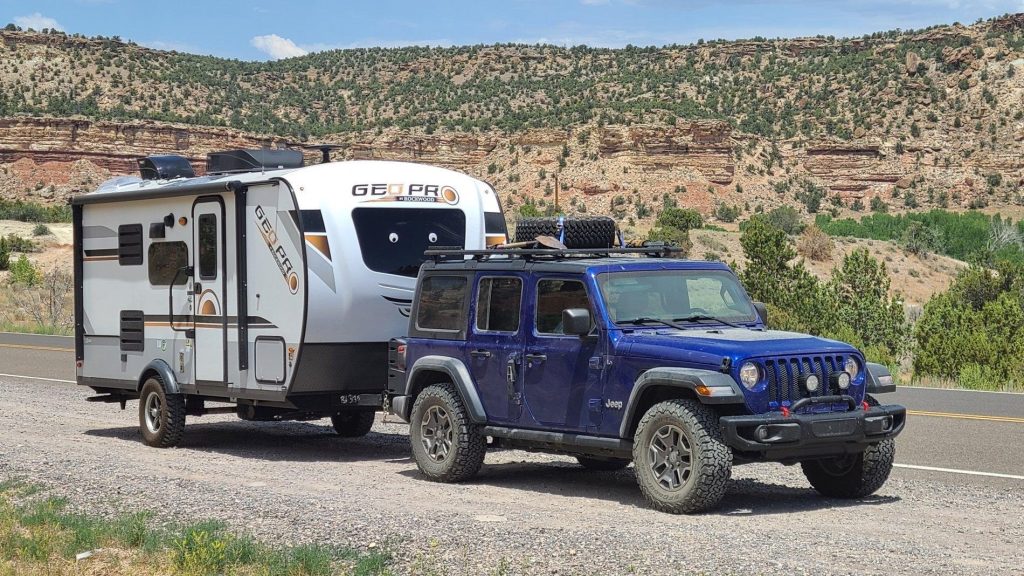 Blue Jeep pulling a Geo Pro Travel Trailer