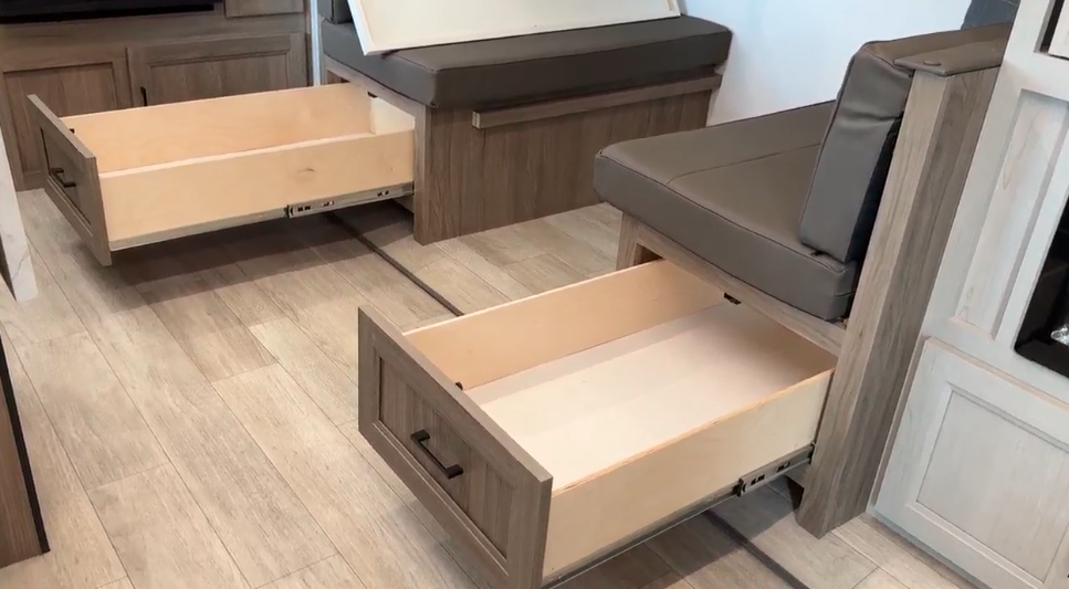 RV dining area with open under-seat storage drawers, showcasing efficient use of space for added convenience. The drawers are built into the sturdy wooden benches, perfect for organizing belongings while maintaining a clean and sleek look.