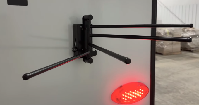 Close-up of a foldable towel rack mounted on the exterior of a GO Explore travel trailer. This practical feature includes four adjustable arms for hanging towels or gear, with a sleek black design near the rear light, enhancing functionality for outdoor activities.