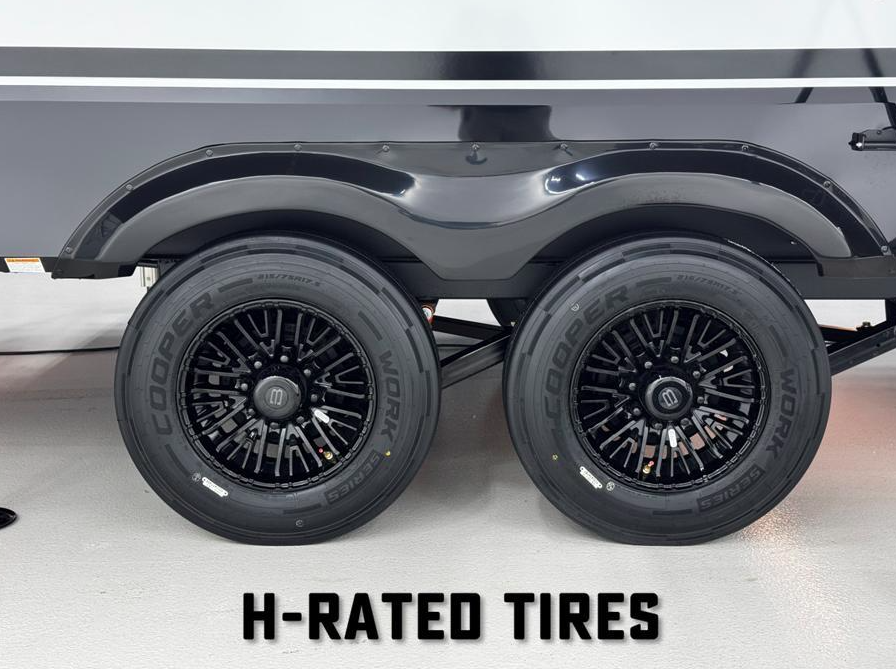 Dual black alloy wheels with Cooper Work Series H-rated tires on a Brinkley RV, shown under a sleek black fender with white RV siding above.
