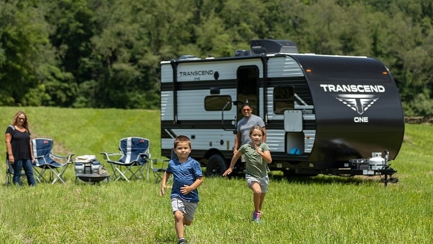family outside their Transcend One camper-- kids are having fun running