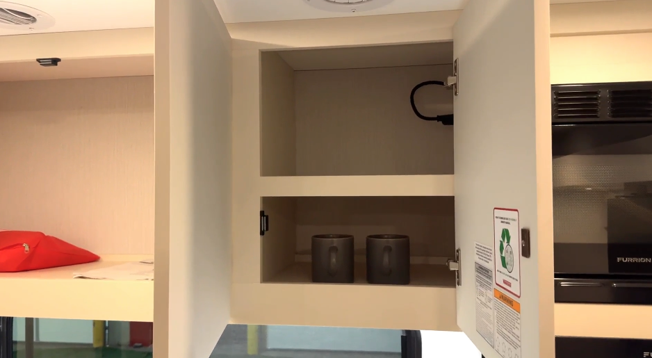 RV kitchen pull-out pantry cabinet with two wooden shelves holding canned goods, cooking oil, and Starbucks coffee pods.









