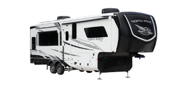 A white and black Jayco travel trailer with dual axles and a modern aerodynamic front cap. The trailer features multiple windows, two rooftop air conditioning units, exterior storage compartments, and a fold-down entry staircase. Designed for towing, it offers a sleek and contemporary RV design.