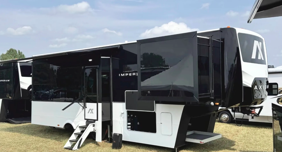Axiom Imperium 12900 fifth wheel luxury RV with dual slide-outs, steel-structured laminated side walls, and modern black and white exterior design displayed at an outdoor RV show.