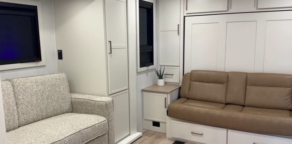 Brinkley RV interior with dual sofas, built-in storage cabinets, and large windows, creating a versatile living and sleeping space.
