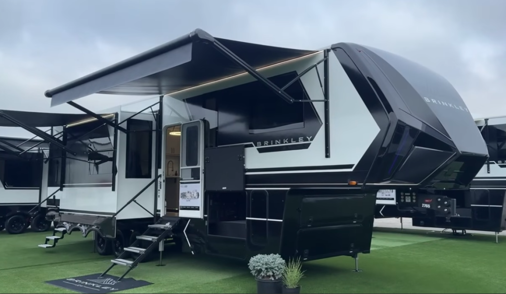 2026 Brinkley fifth wheel RV on display with dual awnings extended, modern front cap design, and luxury exterior styling.