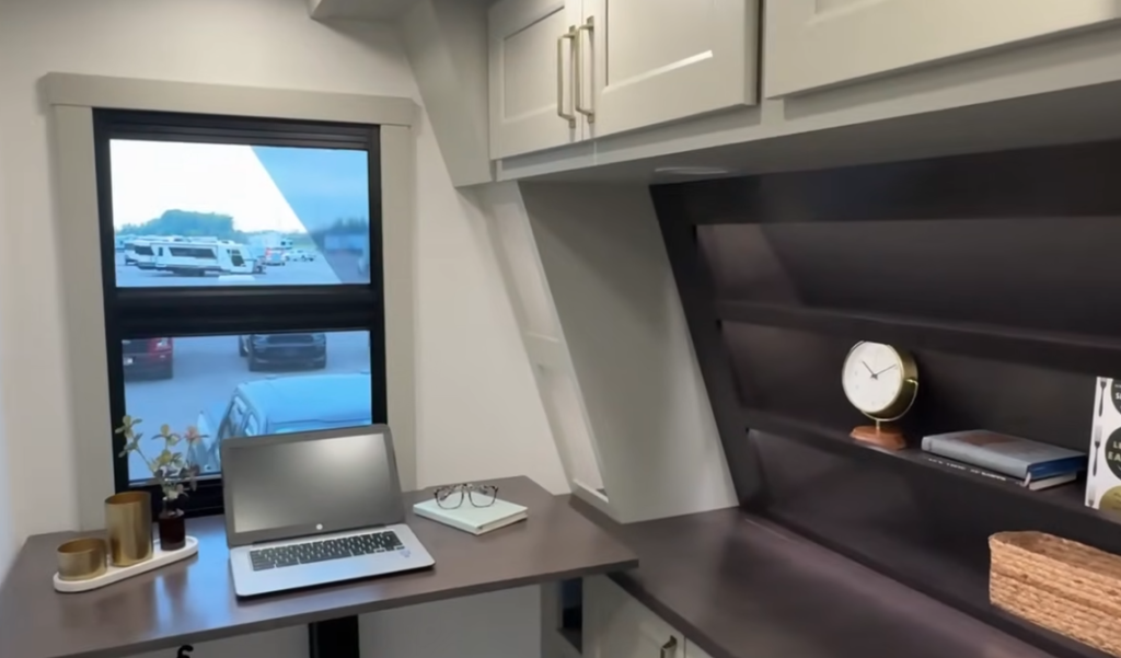 Brinkley RV interior office space with desk, laptop, storage cabinets, and shelving, designed for remote work and extended RV travel comfort.