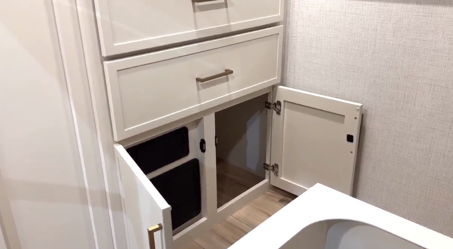Bathroom storage area inside the Brinkley Model I 280 featuring soft-close drawers, lower cabinet doors, and a linen-style wall finish. The open cabinet reveals deep shelving beneath the sink, offering organized space for towels and toiletries while maintaining a clean, modern aesthetic.