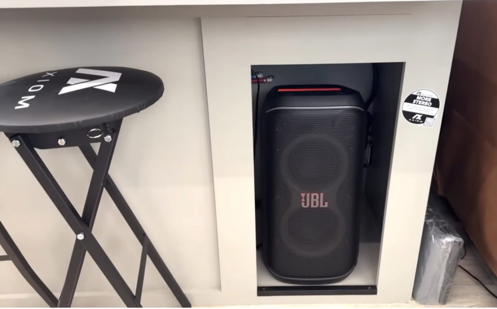 Built-in entertainment nook inside the 2026 Axiom Imperium I3800 fifth wheel featuring a JBL Bluetooth speaker, Axiom-branded folding stool, and integrated storage space designed for enhanced RV audio performance.