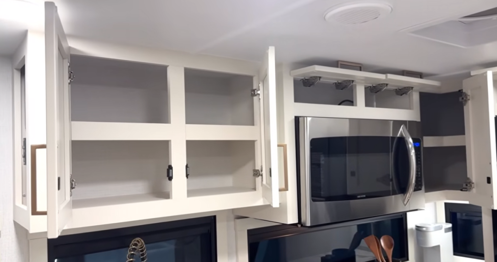 Brinkley Model Ix 20X kitchen overhead storage cabinets open above convection microwave, showing deep shelving and soft-close hardware for organized RV kitchen design.