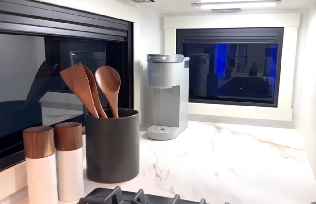Brinkley Model Ix 20X kitchen counter with marble-look surface, Keurig coffee maker, salt and pepper shakers, and wooden utensils beside large panoramic windows.