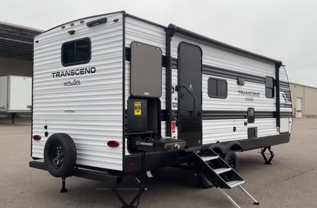 Grand Design Transcend Xplor travel trailer exterior with outdoor kitchen, entry steps, and black-and-white aluminum siding design.
