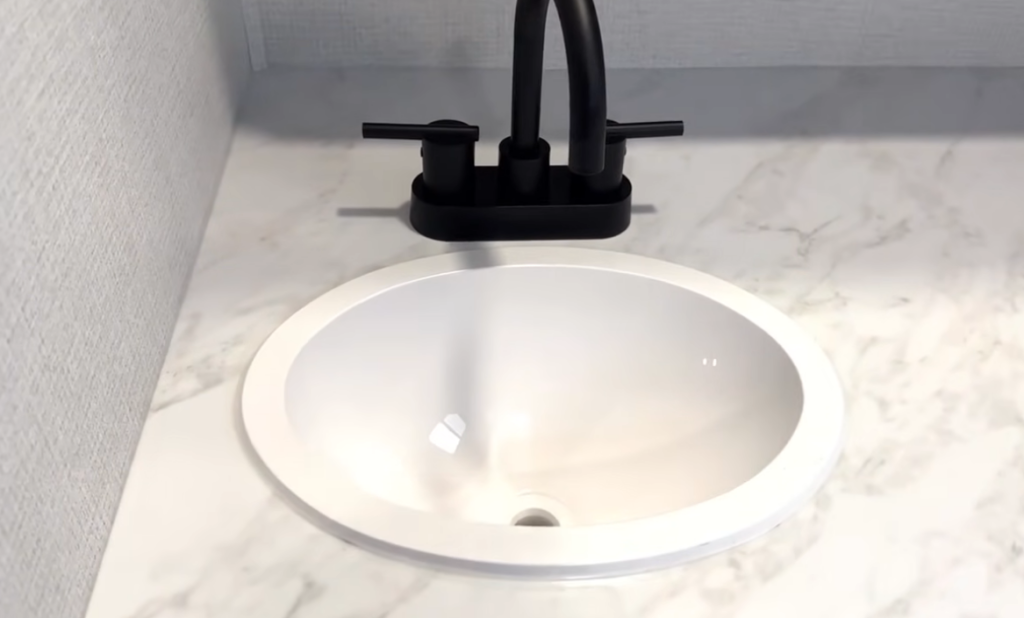 Grand Design Transcend Xplor 22RBX bathroom sink with marble-look countertop and matte-black faucet, highlighting the RV’s modern interior finishes.