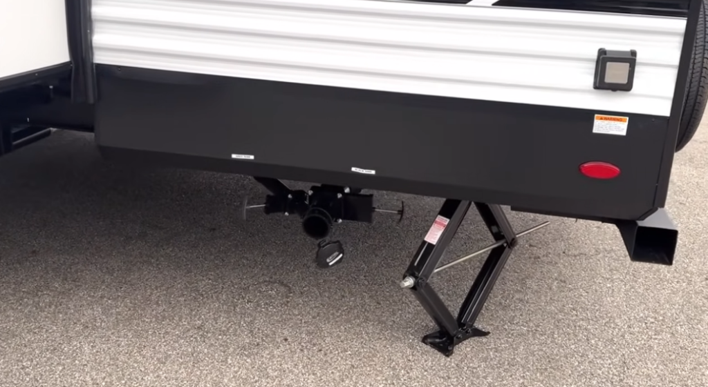 Grand Design Transcend Xplor 22RBX RV rear stabilizer jacks and sewer outlet connection, showcasing the underbelly design and easy-access dump valves for setup and maintenance.