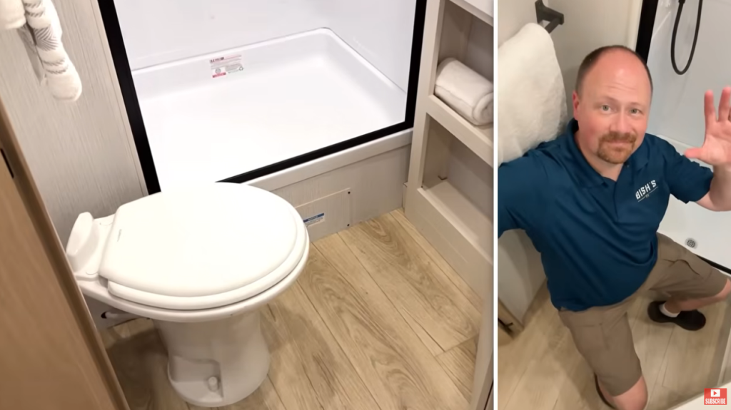 Winnebago Thrive RV bathroom featuring a foot-flush toilet, light wood flooring, open shelving with towel storage, and a spacious shower area; Bish’s RV expert demonstrates the functional layout and legroom of the compact bathroom design.