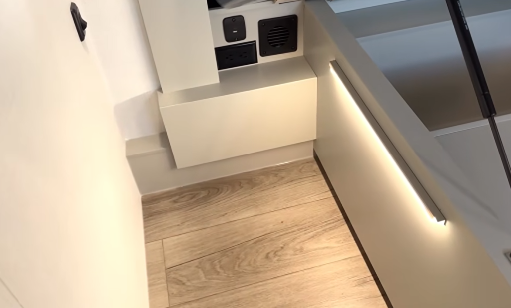 Brinkley Model G Series RV bedroom detail showing bedside outlets, heat vent, and under-bed LED accent lighting, designed for convenience, comfort, and modern functionality.