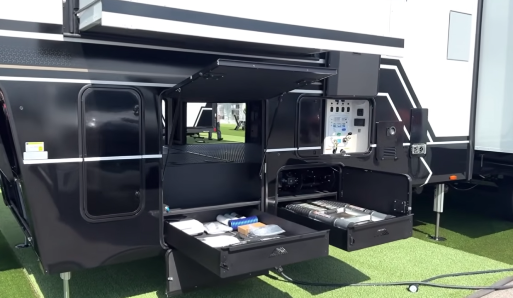 Brinkley Model G Series fifth wheel exterior front storage bays open, displaying dual slide-out utility trays and organized service center, highlighting premium construction and smart functional design.