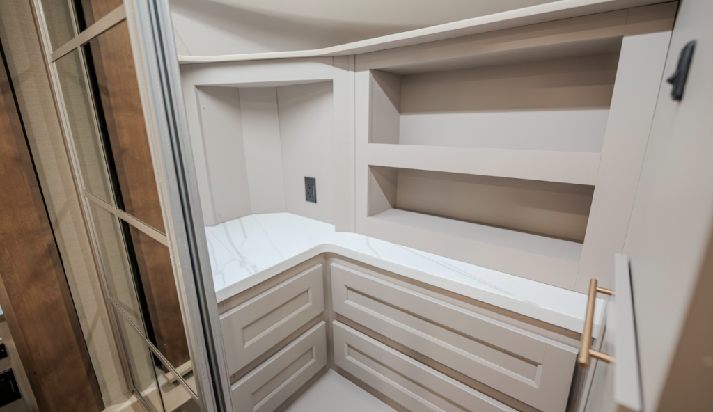 Alliance Paradigm fifth wheel bedroom closet with built-in shelves, drawers, marble-look countertop, and mirrored wardrobe door for organized storage.