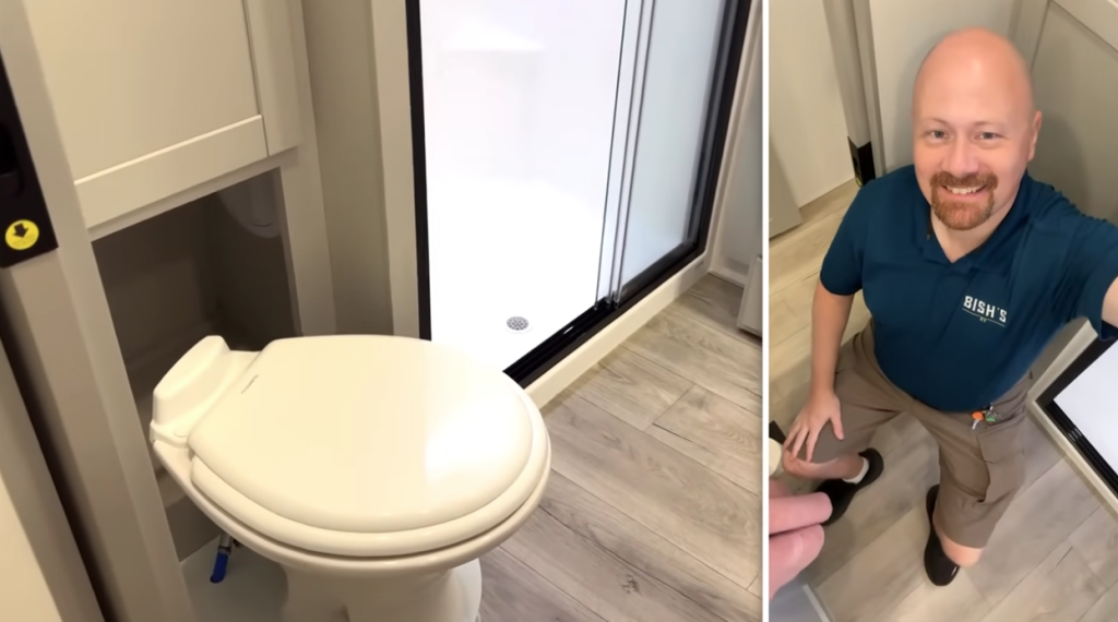 RV bathroom in the Brinkley Model Z showcasing a spacious layout with a porcelain toilet, large shower, and ample legroom, demonstrated by a Bish’s RV team member for scale.