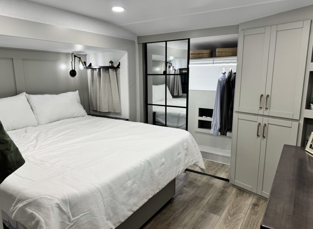 Brinkley Model Z 3600 bedroom with a king-size bed, mirrored wardrobe doors, built-in closet storage, modern lighting, and light gray cabinetry for a residential, upscale feel.