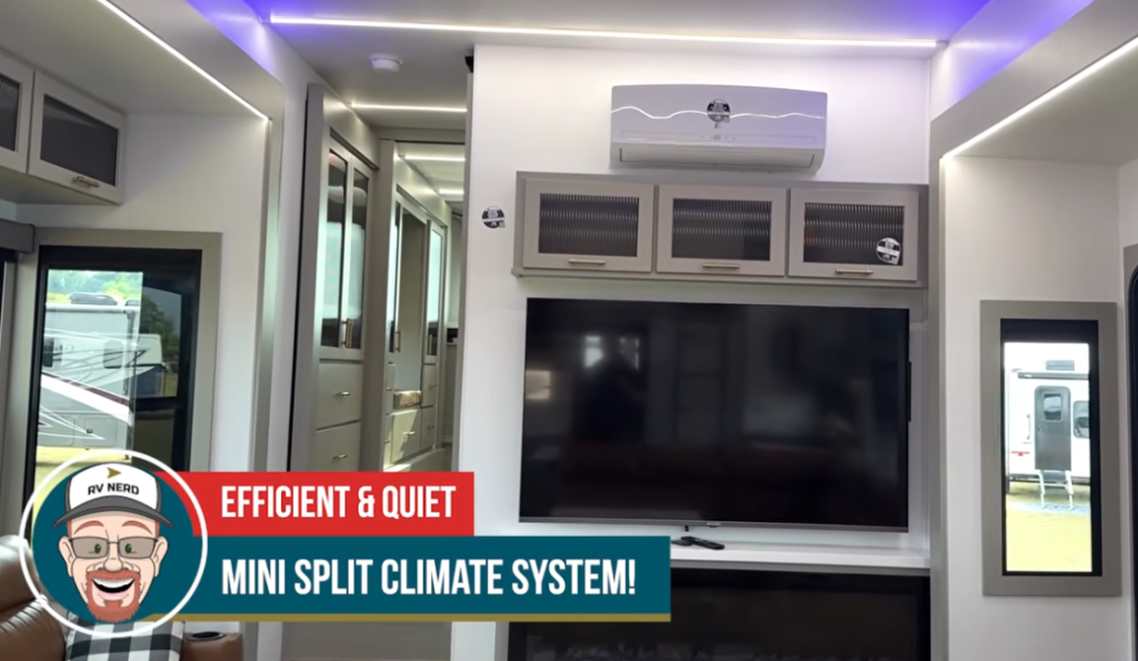 Living area of the 2026 Axiom Vendetta 4250 fifth wheel featuring a large flat-screen TV, electric fireplace, overhead cabinetry, and an efficient mini-split climate control system highlighted for its quiet operation.