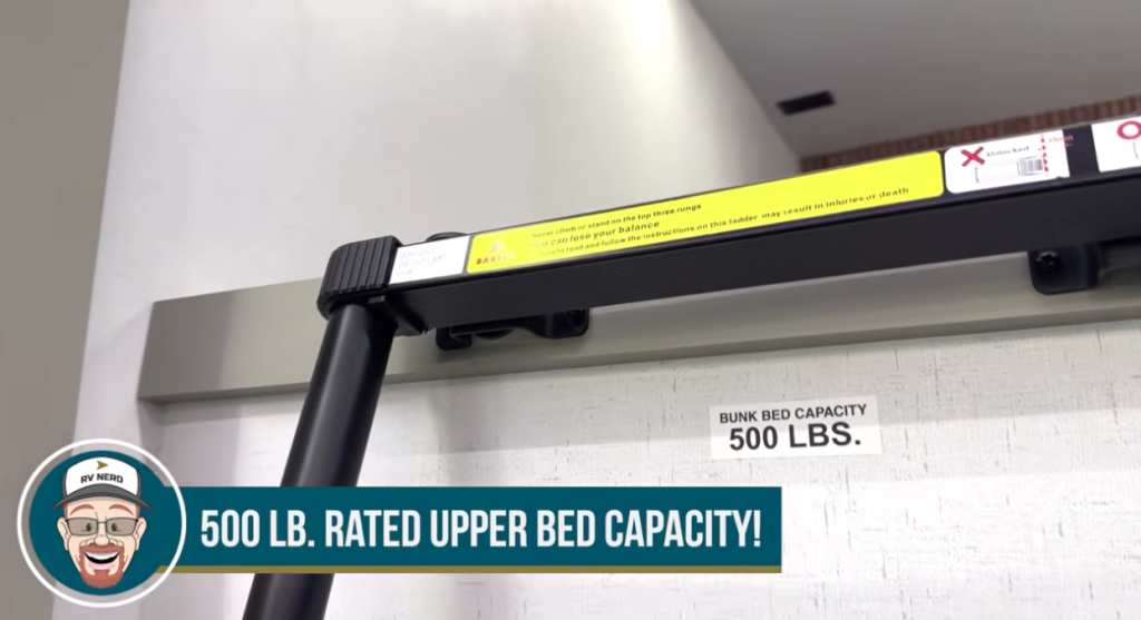 Close-up of the 2026 Axiom Vendetta 4250 loft ladder and bunk area label showing a 500-pound rated upper bed capacity, emphasizing the RV’s strong and family-friendly construction.