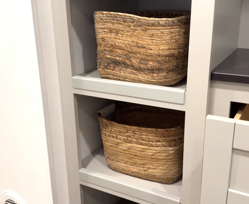Woven wicker storage baskets sitting on built-in gray shelving in an RV bedroom closet, highlighting organized storage space and modern cabinetry.
