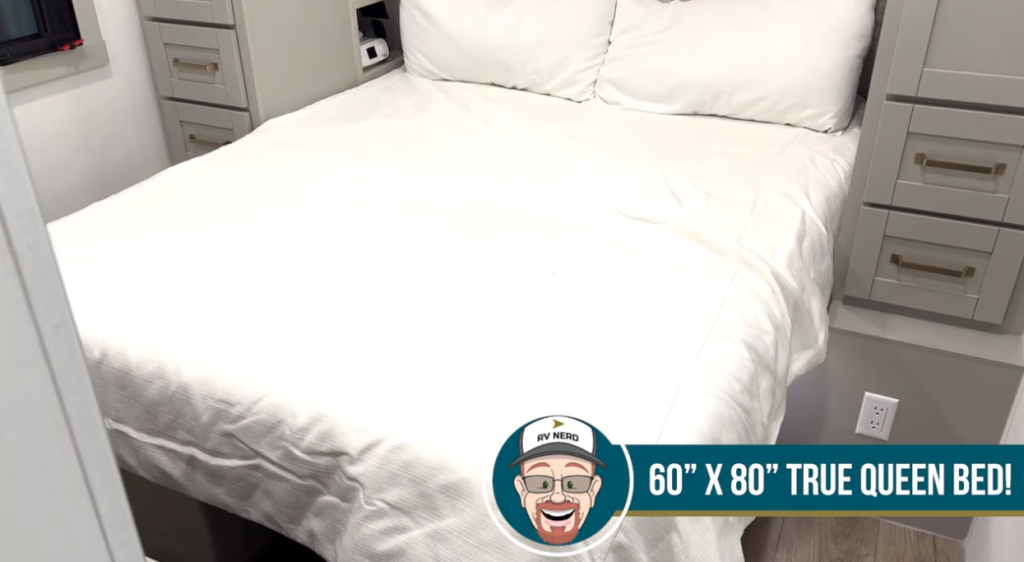 Bedroom in the 2026 Brinkley Model Z Air featuring a 60” x 80” true residential queen bed, built-in bedside storage cabinets, and modern gray shaker drawers for additional organization.