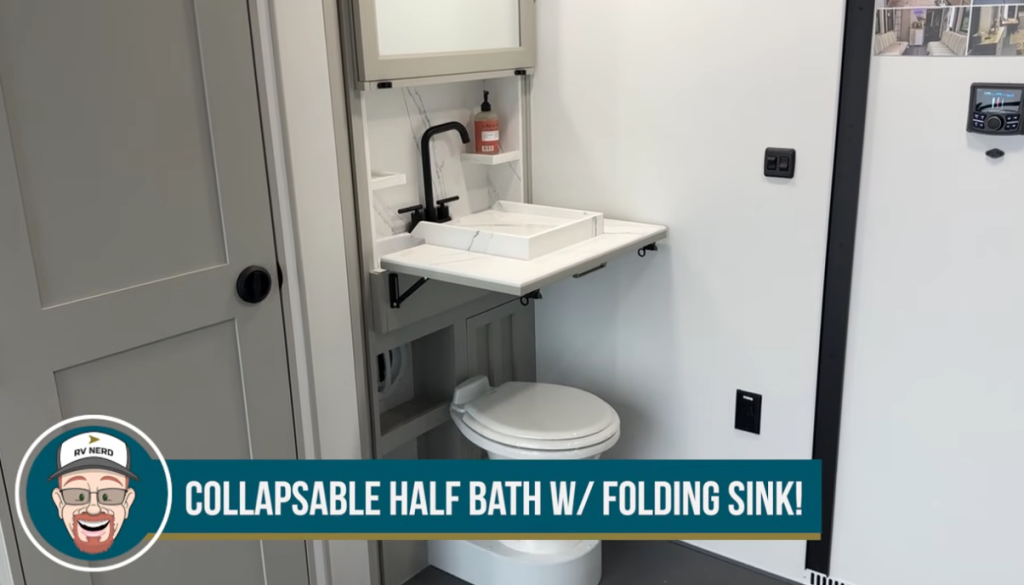 Collapsible half bath inside a Brinkley toy hauler featuring a space-saving folding sink above the toilet, compact storage shelves, and modern fixtures designed for multi-use garage areas.