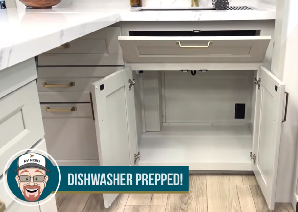 RV kitchen cabinet space prepped for a built-in dishwasher, showing plumbing and electrical hookups ready for installation in a modern Brinkley fifth wheel.