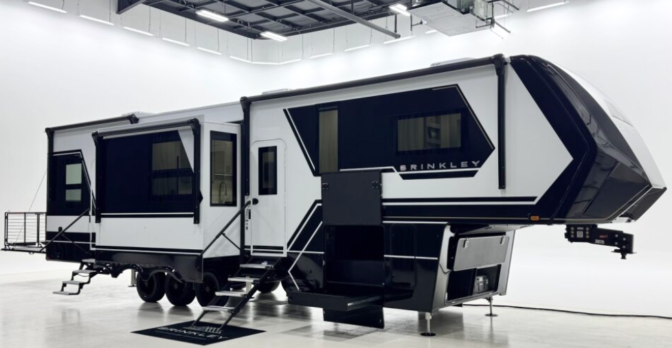 Brinkley Model Z5 luxury fifth-wheel RV displayed in a bright studio, featuring dual slide-outs, modern black-and-white exterior design, and premium build quality.