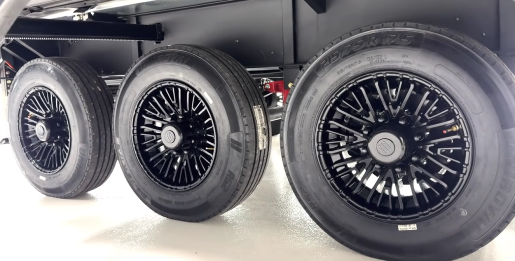 Triple-axle Brinkley RV suspension system featuring three black alloy wheels with 215/75R17.5 tires, showcasing heavy-duty stability and towing performance.