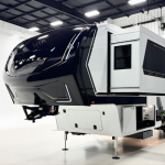Showcasing the Brinkley Model Z 3200 luxury fifth wheel RV highlights its glossy black front cap with prominent Brinkley branding, extending slide-outs, and a well-lit showroom.