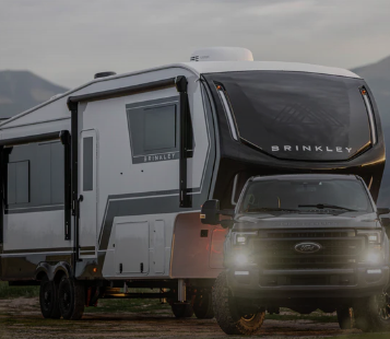 Brinkley fifth wheel RV being towed by a Ford truck at sunset in a scenic outdoor setting