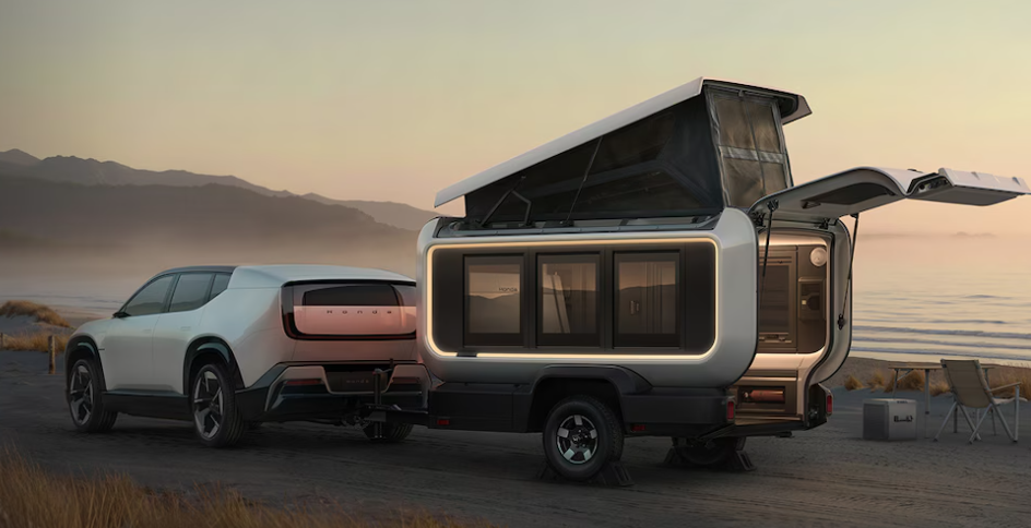 Compact camper trailer with pop-up roof towed by SUV at lakeside campsite at sunset