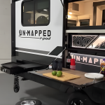 Unmapped R-Pod travel trailer rear outdoor kitchen with fold-down prep table and serving window