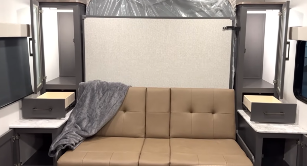 RV interior with sofa sleeper and overhead Murphy bed folded down between dual wardrobes