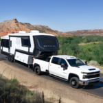 Brinkley fifth wheel RV being towed by a white heavy-duty pickup on a desert highway