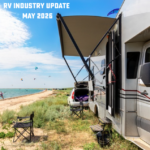 Travel trailer parked by a lakeside beach with awning extended, chairs set up outside, and text overlay reading “RV Industry Update May 2026.”