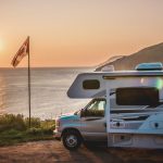 RV Motorhome parked at sunset in front of lake near Canadian flag