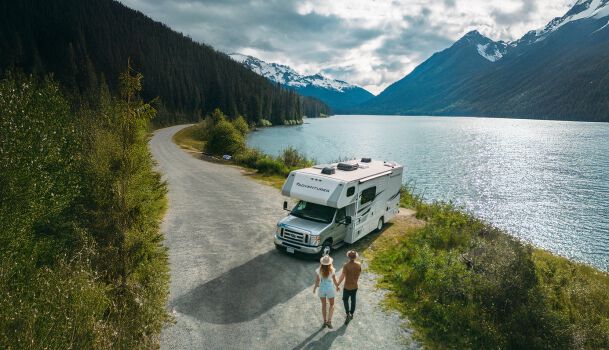 Couple walking toward RV parked on highway near lake in Canada