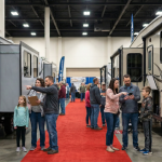 Shoppers comparing RV floorplans at an indoor RV show in Novi, Michigan.